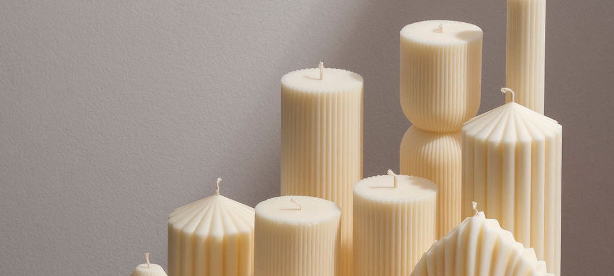 Conjunto de velas moldadas em cera marfim sobre uma mesa clara